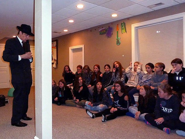 Hypnotist Mister Vibe speaks to two dozen tween girls at a Chicago area home hypnosis show.