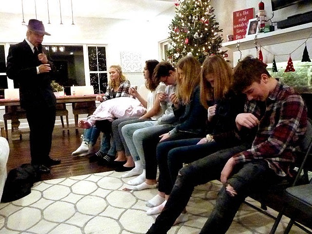 A row of seated teens imagining they're licking ice cream cones at a Chicago area Sweet 16 party hypnosis show.