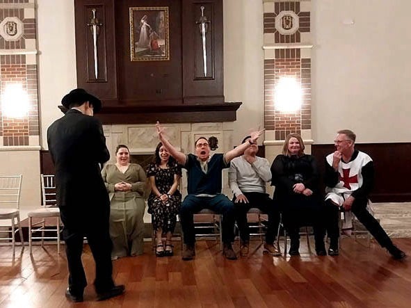 A man spreads his arms and shouts at a Chicago area corporate holiday hypnosis show.