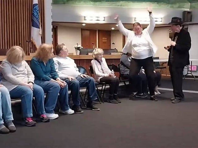 Woman jumps up from her seat at Chicago area social club hypnosis show.