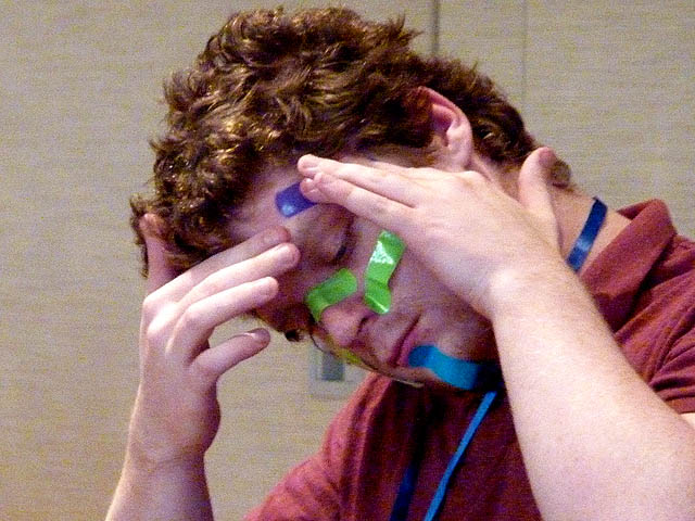 Volunteer triggered to put bandages on his face at Chicago area corporate hypnosis show.
