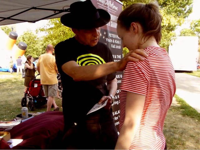 Hypnotist Mister Vibe giving suggestions to hypnotized girl at a Chicago park festival.