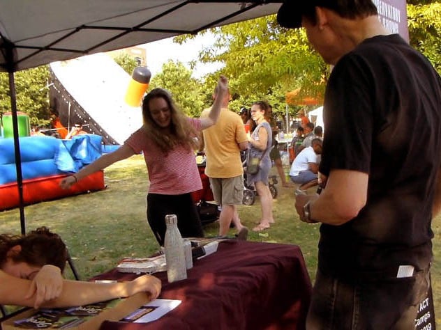 Hypnotist Mister Vibe watches hypnotized girl dance at a Chicago park festival.