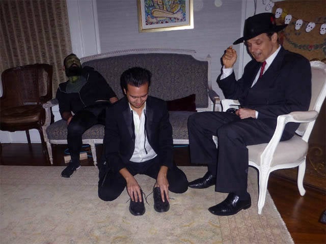 Hypnotized man kneeling on the floor unable to lift his shoes at a Chicago house party.
