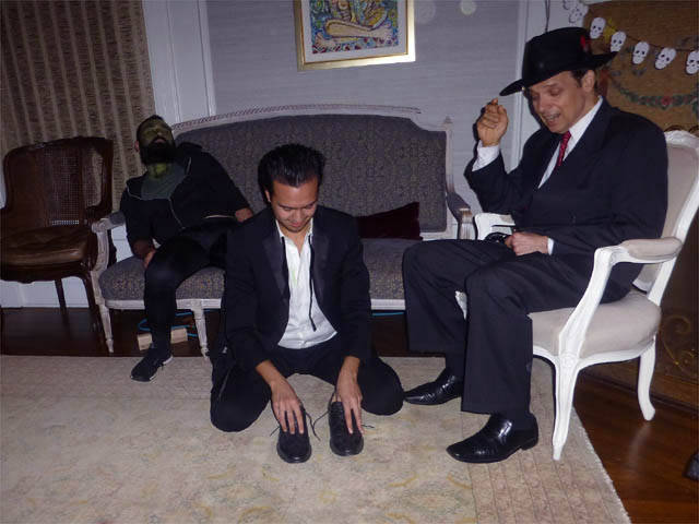 Hypnotized man kneeling on the floor unable to lift his shoes at a Chicago house party.