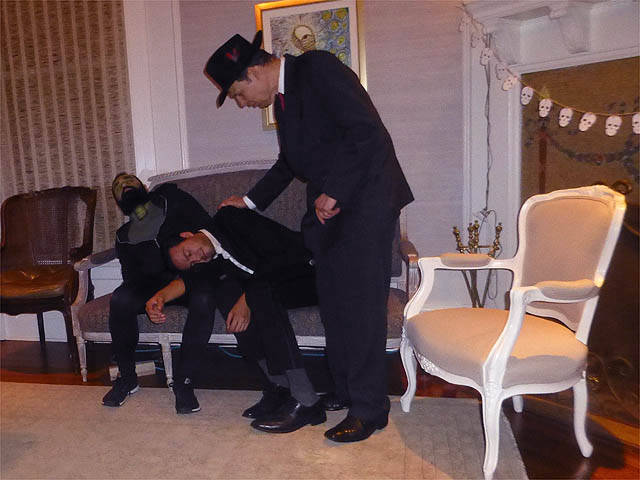 Two men slump over in hypnosis on a couch at a Chicago house party.