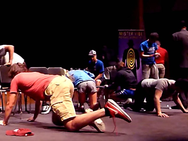 Students crawl on stage at Chicago area high school graduation hypnosis show.