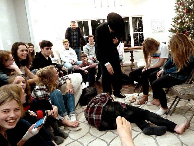 A group of teens looking at a boy laying on the floor at a Chicago area Sweet 16 party hypnosis show.